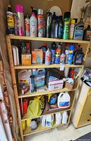 Metal shelving stocked with assorted car care products including sprays, oils, and fluids.