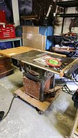 Beaver table saw with base and caster dolly, saw blades on top, and crank handle for fence adjustment visible.
