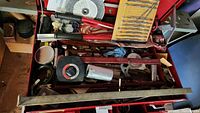 Top view showing drill bits, sanding discs, screwdrivers, sockets, and some pliers arranged in a toolbox drawer
