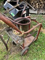 Red two-wheel cylinder cart with attached hoses and regulator