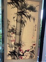 Angled close-up showing bamboo, branches, and pink blossoms with shadow effects.