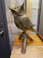 Full view of the brass owl sculpture standing on a branch base showing overall size and shape.