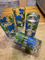 Clear drinking glasses with colorful blue and green flower prints photographed on a wooden surface.