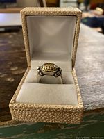 Front view of ring in open jewelry box on wooden surface