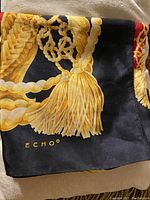 Close-up image showing gold tassel and chain design on black background with 'Echo' brand printed.