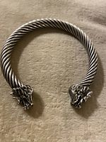 Clear top-down view of the silver cuff bracelet showing the twisted band and dragon head details at each open end.