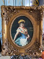 Full view of Victorian oil painting of a young woman in vibrant clothing inside an ornate gold frame with intricate carving.