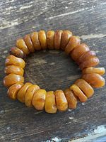 Full view of the stretch amber bracelet on rustic wooden surface.
