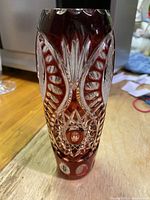 Front and detail view of ruby red Bohemian crystal vase showing intricate cut patterns and polished finish.