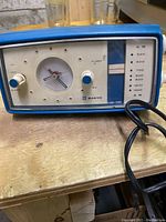 Front view of the vintage blue plastic desk clock radio showing analog clock, AM radio tuner scale, and control knobs.