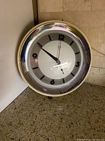 Photo of full clock front showing clock face, metal casing, and hands