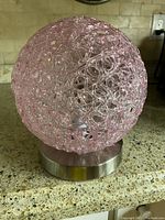 Front view of the pink spaghetti glass globe lamp on chrome base, showing woven glass design and detail of the base.