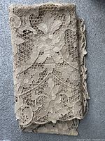 Folded lace table cloth showing the detailed 1970s floral lace design with openwork and scalloped edges.
