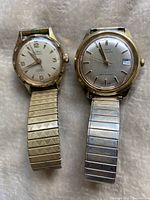 Two vintage automatic men's wristwatches side by side, showing both watch faces, one Le Roy and one Timex.