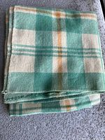 Folded wool blanket showing the plaid pattern and stitching.