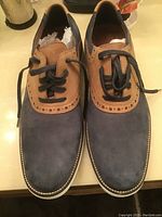 Front view of Crown & Ivy men's suede oxford dress shoes showing the dark blue and tan color combo, black laces, and brogue style details around lace area.
