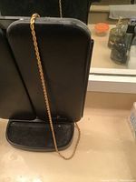 Full length of gold tone rope chain shown hanging on black display stand, showing rope design and length.
