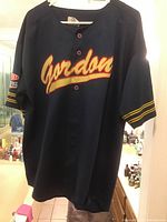 Full front view of navy blue Gordon #24 NASCAR racing jersey with button collar. 'Gordon' text across chest.