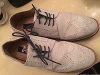 Side and top view of left and right suede oxford shoes showing perforated brogue pattern and black laces.