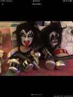 Photo of two Kiss highlight collectible dolls with artist signatures, showing face paint detail and costumes.