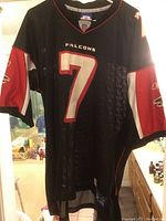 Front view of black mesh Michael Vick Atlanta Falcons football jersey with number 7 in white and red, black with red and white sleeve panels.