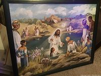 Full view of framed religious wall art showing Jesus baptizing a person in water with several observers around outdoors in a natural setting.