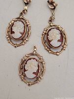 Pair of cameo earrings and pendant arranged on light background