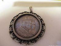 Front side of the pendant showing the silver Thaler coin with two crowned busts and ornate silver frame.