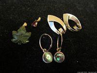 Overview of two pairs of earrings and two pendants on black background showing the materials and design details.