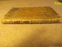 Spine view showing red and black title labels and gilt decoration on leather spine