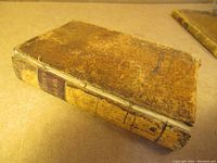 Overall view of the antique leather-bound book showing the worn distressed cover and spine.
