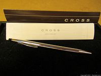 Silver Cross ballpoint pen placed on black felt surface with original paperwork and packaging insert.
