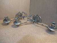 Pair of antique metal Art Nouveau swivel sconces side view showing two candle holders each and symmetrical design.