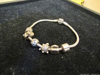 Full view of the silver Pandora style bracelet showing all charms and overall design on a black background.