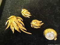 Full set of pendant watch, brooch, and earrings shown on black background.