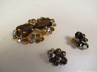 Photo of Sherman clip earrings with clusters of dark faceted rhinestones and unmarked rhinestone brooch with amber and yellow stones.