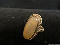 Close-up photo of the ring showing the top face with an oval opal stone set in a decorative sterling silver bezel.