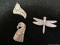 Three items shown together on black background: two First Nations style pendants and a dragonfly brooch