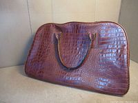 Front and one side of vintage brown carry-on bag with faux crocodile pattern and dual handles