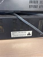 Close-up photo showing the back vented panel of an electronic device with warning label about electric shock risk.