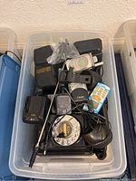 Plastic bin with assorted cell phones (Nokia, Motorola), phone chargers, and a black rotary dial phone