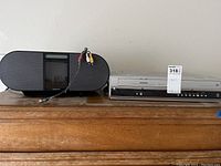 Photo showing Toshiba VHS/DVD player and Sony stereo system side by side on wooden surface.