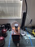 View of all items in the lot together - tower fan, two space heaters, a floor lamp, and other miscellaneous items