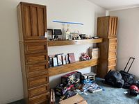 Full view of wooden headboard against wall with two side cabinets and horizontal shelves above several boxes and items on the floor.