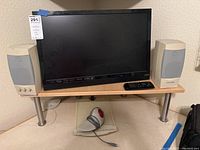 Photo of TV on wooden table with Gateway 2000 speakers on each side, remote on table, and wired mouse on floor below.