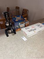 Photo showing the Great American Steakhouse Onion Machine, kitchen tools, boxes including Food Lovers 21 Day Transformation and other kitchen items on a countertop.