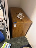 Side and top view of the wooden 2 tier shelf packed against the wall. Shows the size and the wood finish.