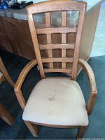 Close-up of one wooden chair showing lattice backrest and white cushioned seat with stain.