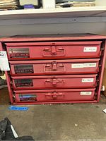 Front-facing photo showing red 4-drawer toolbox with labels on each drawer and latch handles.
