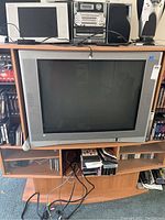Front and side views of the 36-inch Toshiba CRT TV showing silver frame and integrated side speakers placed on wooden TV stand with cables visible.
